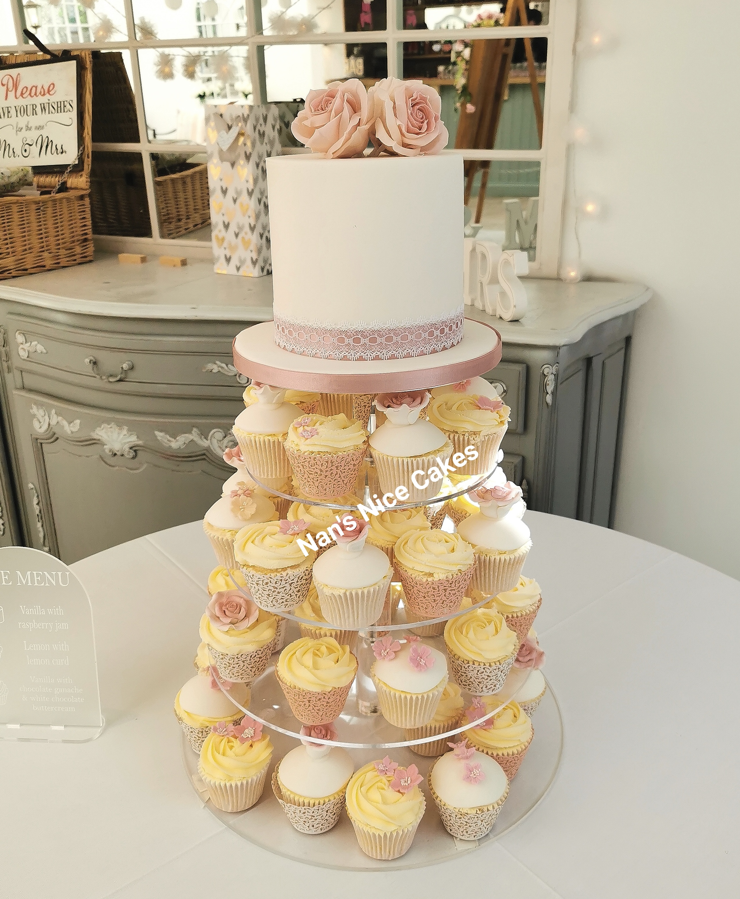 Wedding cake with tower of cupcakes below peach and yellow