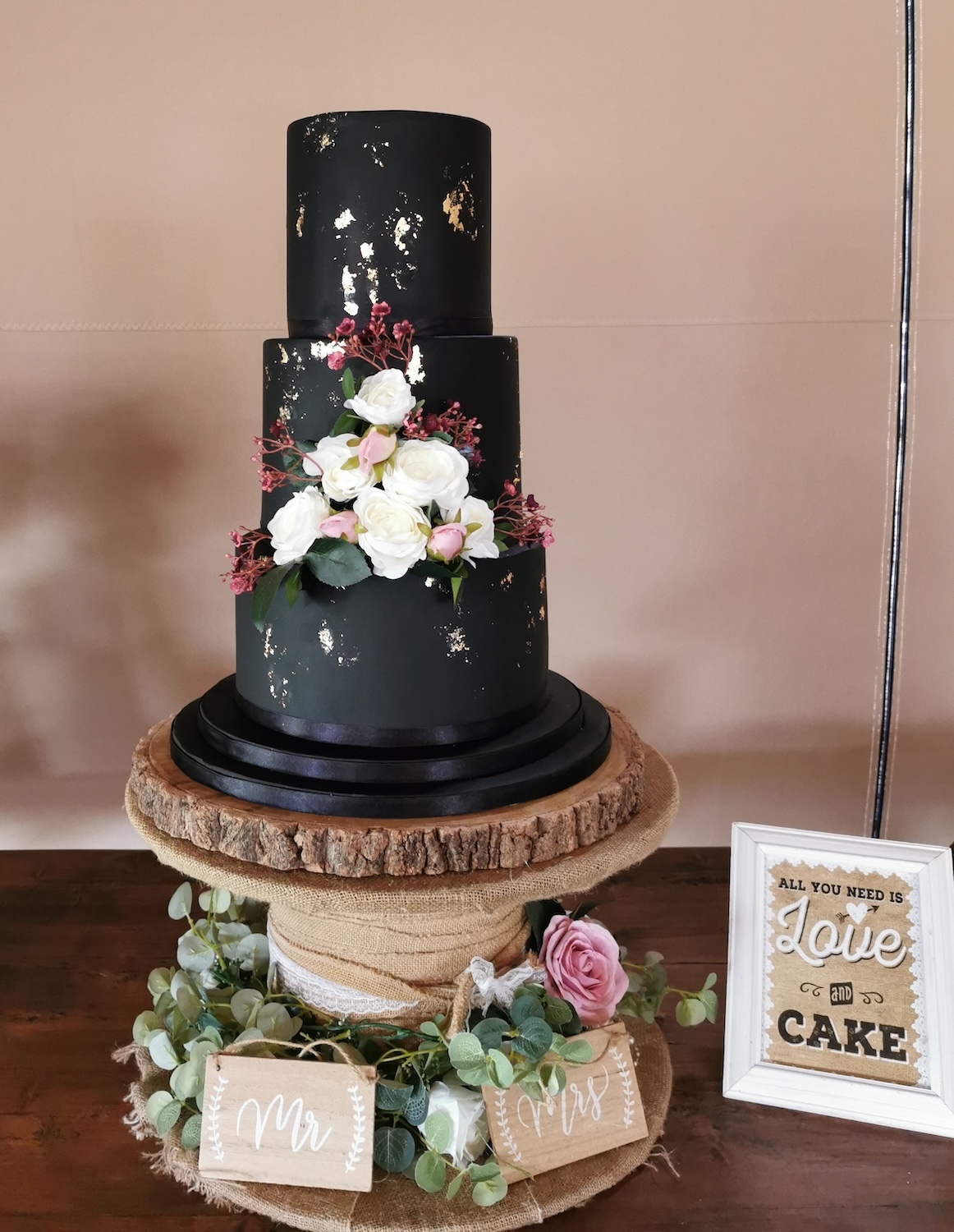 solid black 3 tier wedding cake with gold leaf and white roses