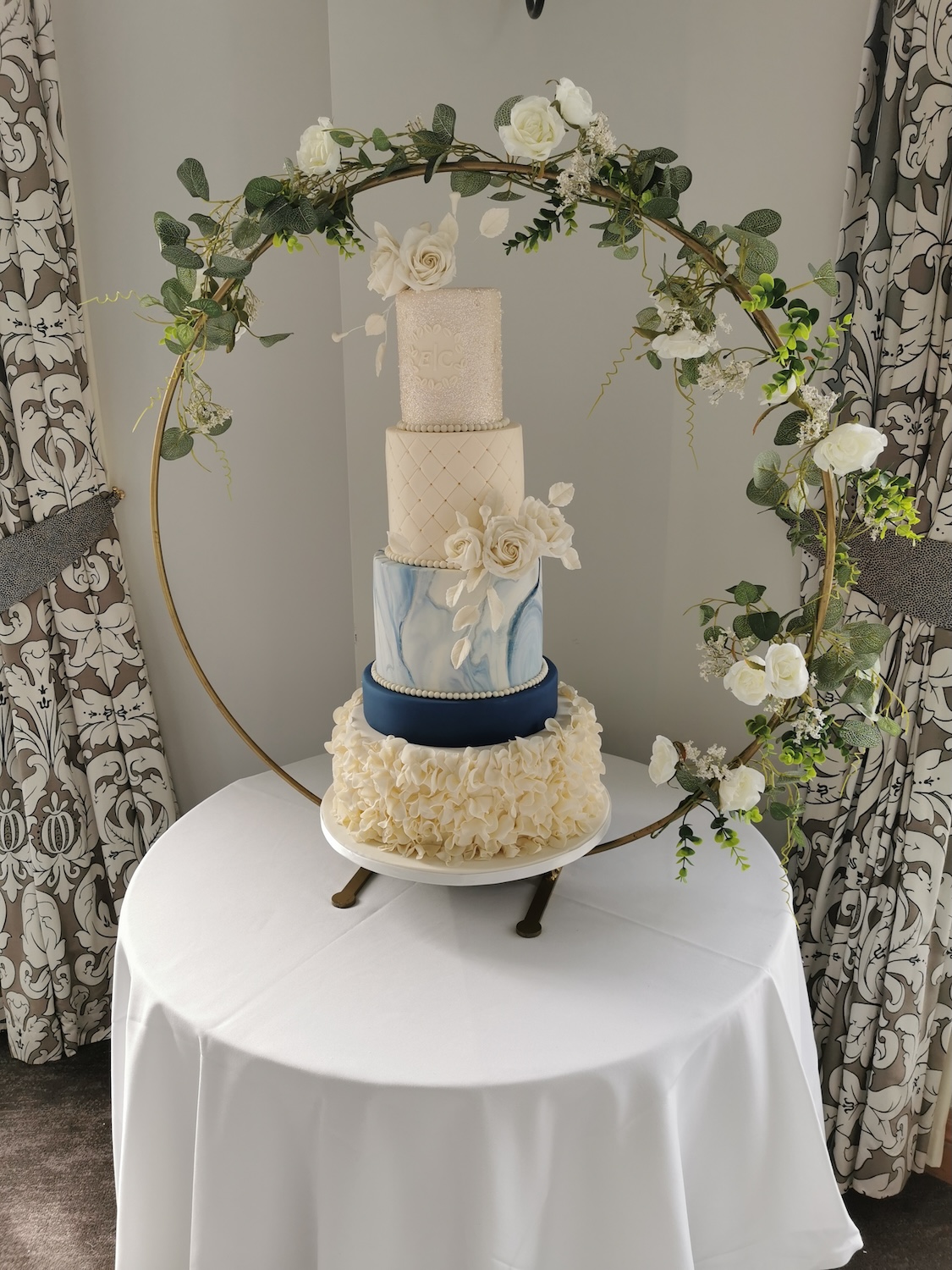 white and blue wedding cake with ruffles and roses