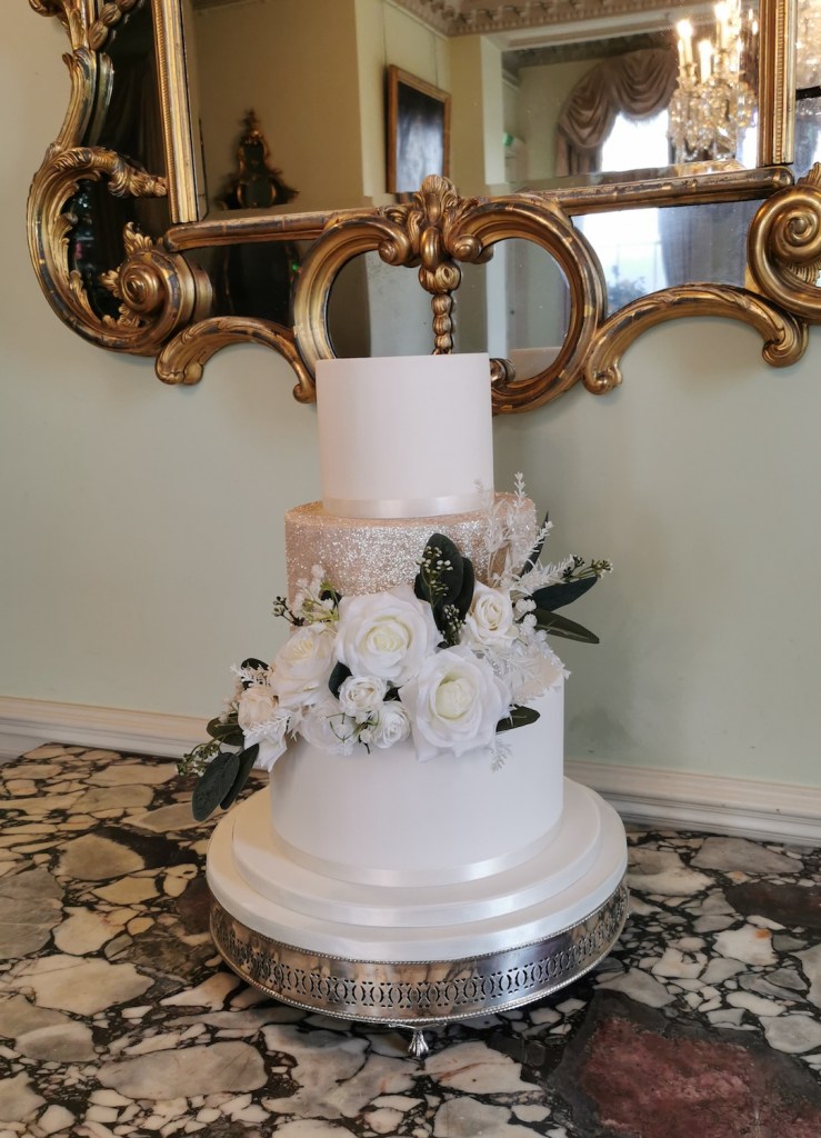 white and rose gold wedding cake with white roses