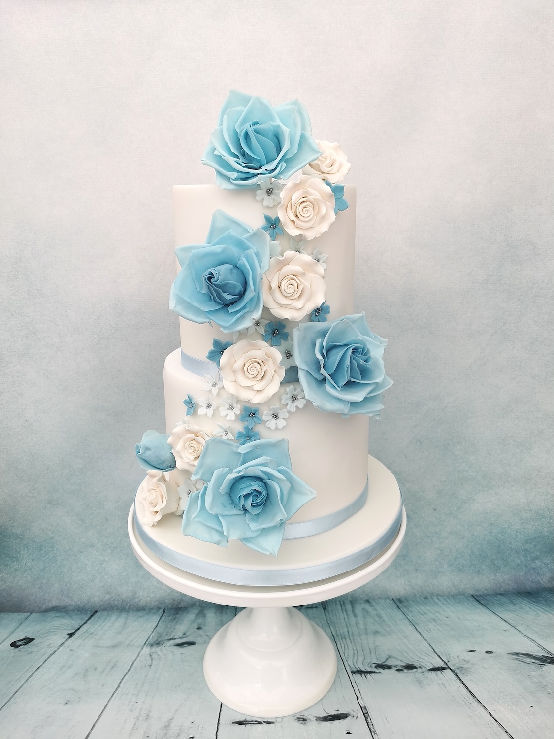 white wedding cake with blue and white roses