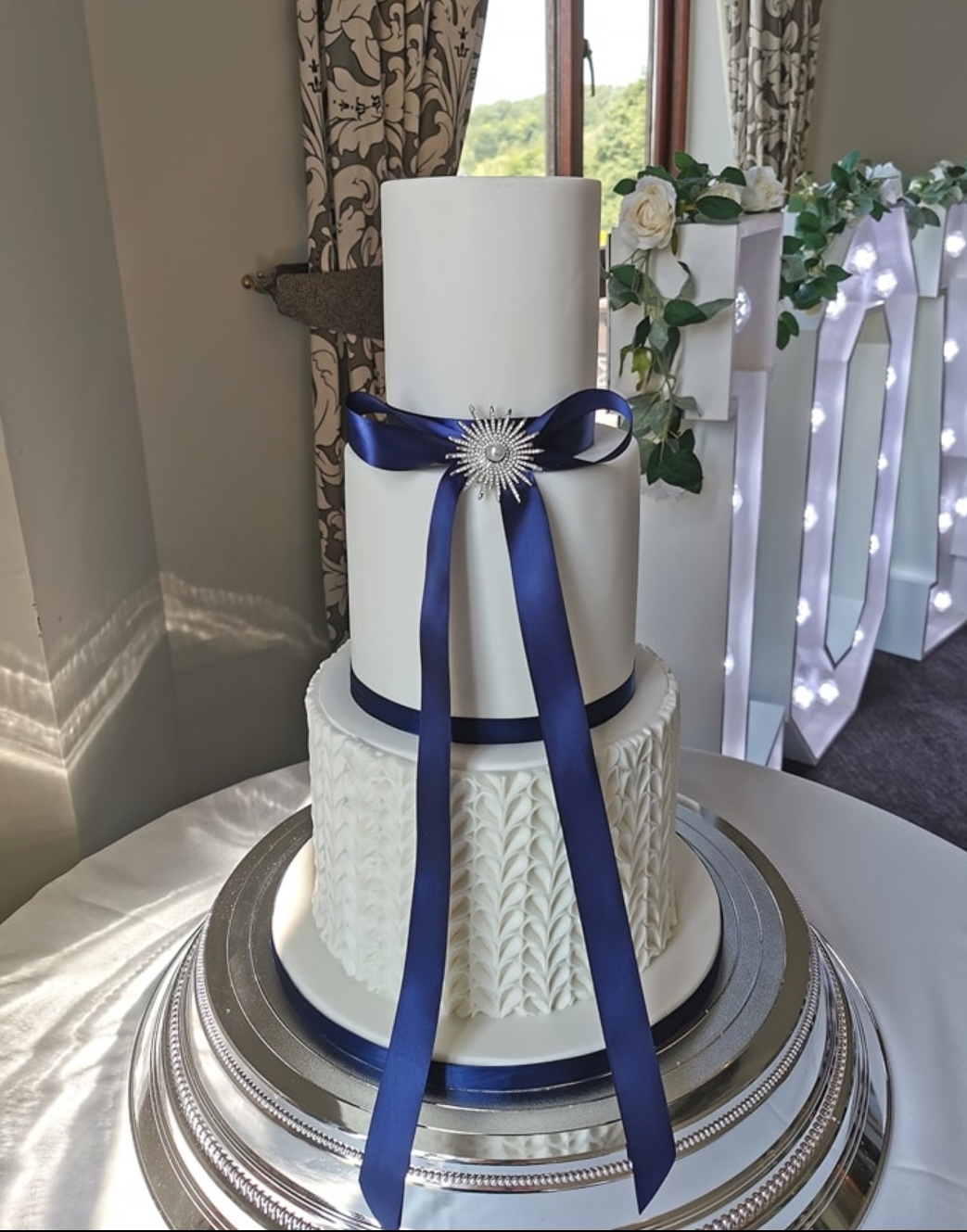 white wedding cake with navy ribbon